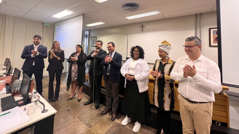 Na foto, há uma sala de aula ampla e bastante iluminada da PUC-RS. Os secretários e diretores dos departamentos da SJCDH estão em pé diante da turma do curso de defesa do consumidor e realizam uma salva de palmas de encerramento do evento.
Autoria da descrição da foto: Wagner Meirelles Ascom SJCDH